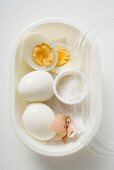 Boiled eggs and salt in plastic food storage container