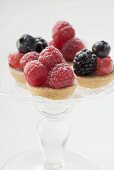 Several berry tarts on cake stand