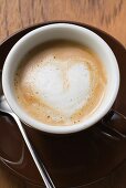 Espresso with milk froth in shape of heart (overhead view)