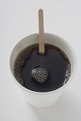 Schwarzer Kaffee im Pappbecher mit Holzstäbchen