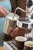 Woman frothing milk with espresso machine