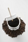 Black coffee in plastic cup on coffee beans