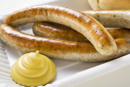 Sausages (bratwursts) with mustard on paper plate