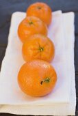 Vier Clementinen auf weißem Tuch