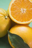 Orangen, ganz und halbiert, mit Blatt