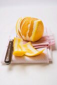 Peeled orange on tea towel with knife