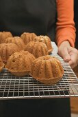 Hands holding freshly baked cakes on cake rack