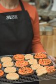 Woman holding Halloween biscuits on cake rack