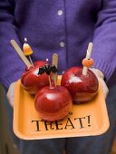 Woman holding tray of toffee apples for Halloween
