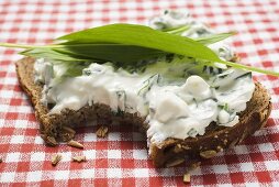 Quark and ramsons on wholemeal bread, a bite taken