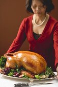 Woman serving roast turkey garnished with fruit