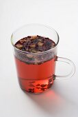 Fruit tea with tea leaves in glass cup