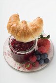 Berry jam, croissant and fresh berries on plate