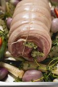 Roher Schweinerollbraten mit Gemüse auf Backblech