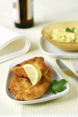 Breaded chicken escalopes, potato salad in background