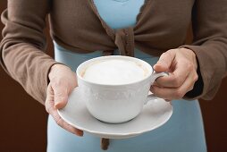 Frau hält Tasse Cappuccino