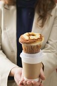 Woman holding muffin and cup of coffee