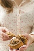 Woman holding halved muffin on checked napkin