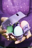 Woman holding egg box full of coloured eggs