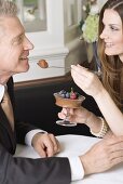 Frau reicht Mann Löffel mit Schokoladencreme im Restaurant