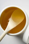 Honey in plastic container with wooden spoon