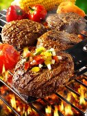 Burgers with vegetables on barbecue rack and spatula