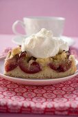 Piece of plum cake with cream in front of coffee cup