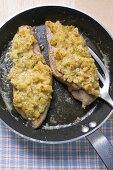 Fish fillets with bread crust in frying pan