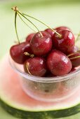 Cherries in plastic tub on slice of watermelon