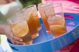 Woman taking glass of iced tea from tray
