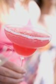 Hand holding a pink cocktail