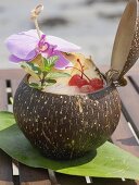 Kokosnussdrink mit Ananas, Cocktailkirsche und Orchidee