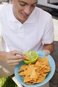 Young man eating tortilla chips with guacamole