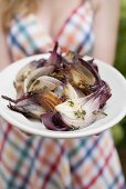 Woman holding a plate of grilled red onions