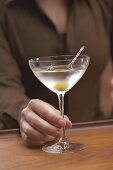 Frau hält Glas Martini mit Olive