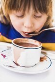 Kind schlürft Kakao vom Löffel