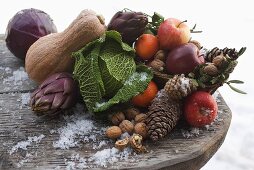 Stillleben mit Äpfeln, Gemüse, Nüssen und Zapfen auf Holztisch