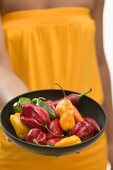 Woman holding a dish of assorted chillies