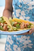 Woman holding plate with two tacos