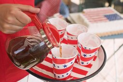 Woman pouring coffee into a paper cup (4th of July, USA)