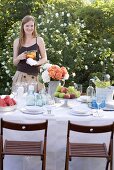 Frau mit Krug Eistee am gedeckten Tisch im Garten