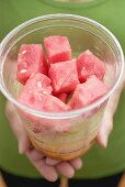 Woman holding plastic tub of diced melon