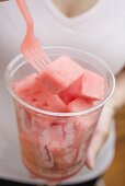 Woman eating diced melon out of plastic tub