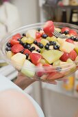 Woman eating fruit salad out of large plastic bowl