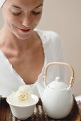 Woman holding tray with tea and white flower