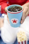 Woman holding beaker of cola with ice cubes