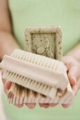 Woman holding olive soap, soap dish and brush