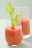 Glass of carrot juice with celery, jug in background