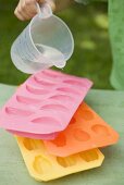 Child pouring water into ice cube tray