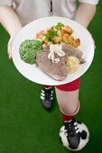 Footballer holding plate of boiled beef with accompaniments